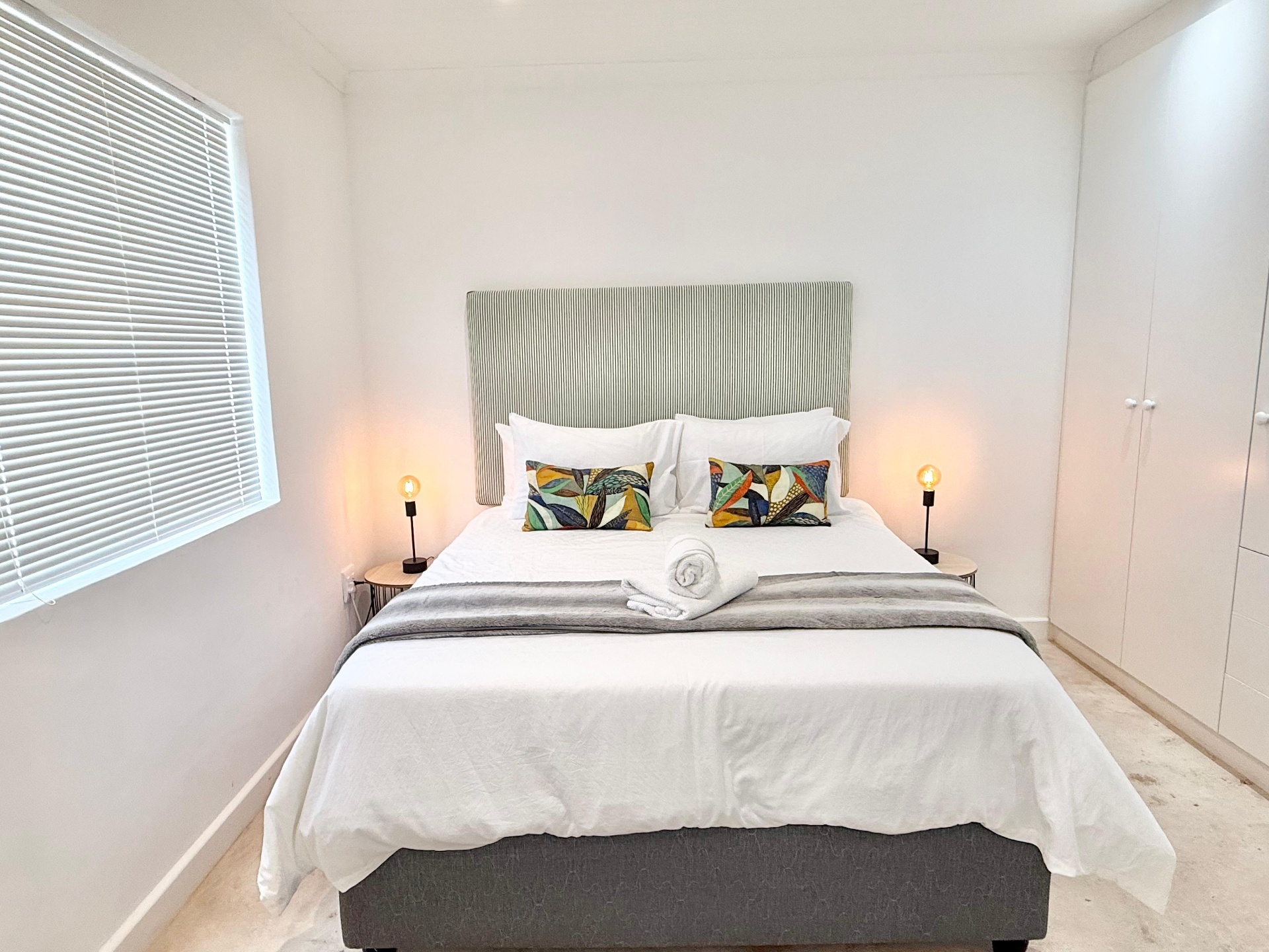 Bedroom with striped headboard and botanical cushions